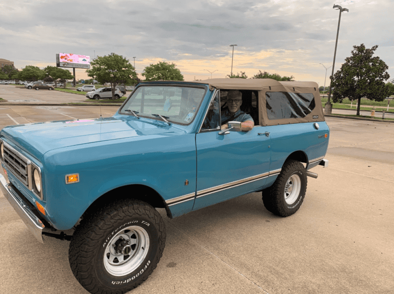 A blue vintage SUV with a tan soft top sits on concrete under cloudy skies, evoking calm for mediation services.