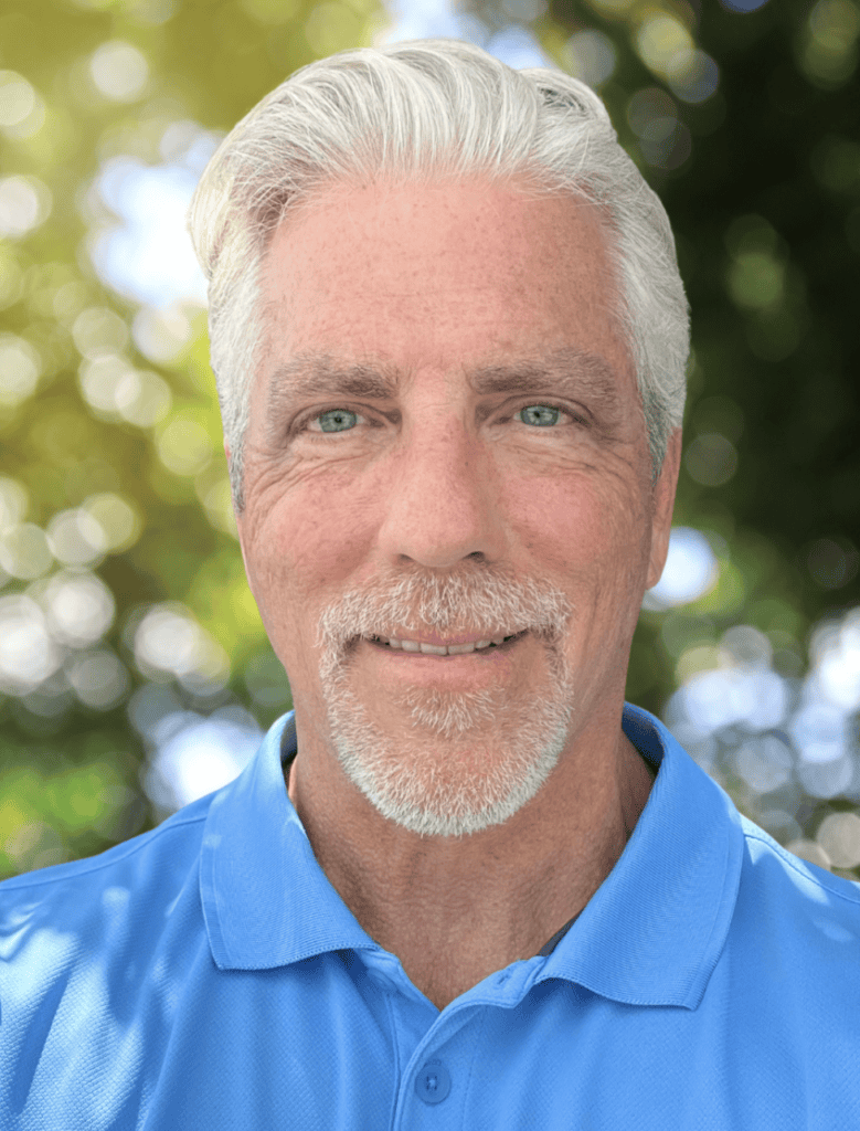 Older man with white hair and a goatee, wearing a blue polo, stands outdoors; experienced legal mediator for complex cases.