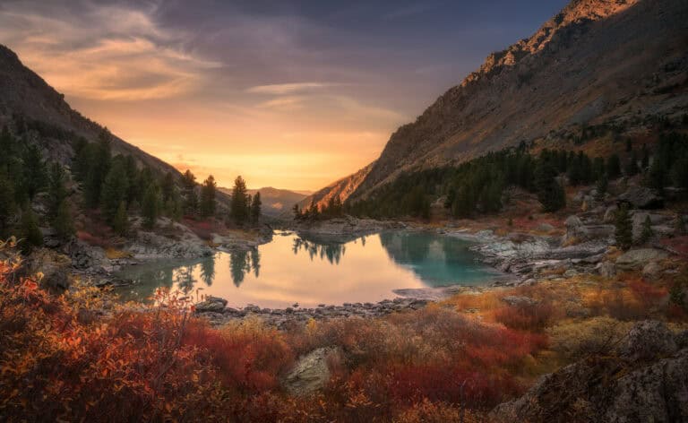 A tranquil mountain lake at sunset, surrounded by trees; peaceful like mediation calmly settling disputes.