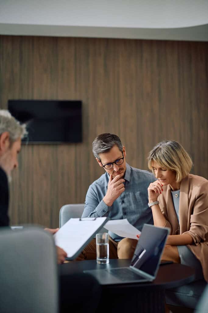 Three people in an office review documents, seriously discussing mediation for longshore and harbor claims.