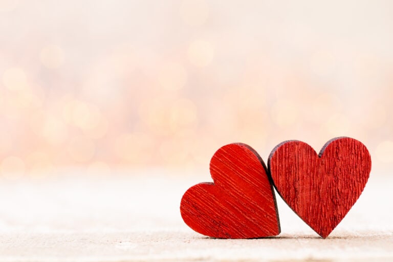 Two red wooden hearts placed together represent harmony achieved through workers’ compensation mediation services.