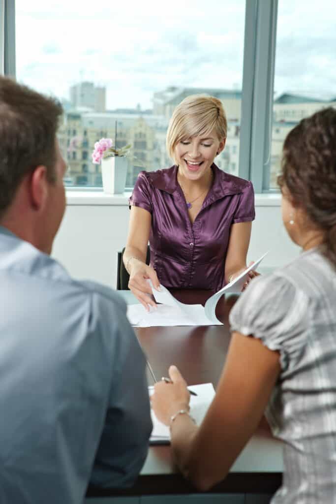 A woman in purple gives papers to two colleagues in an office, illustrating workers’ compensation mediation.