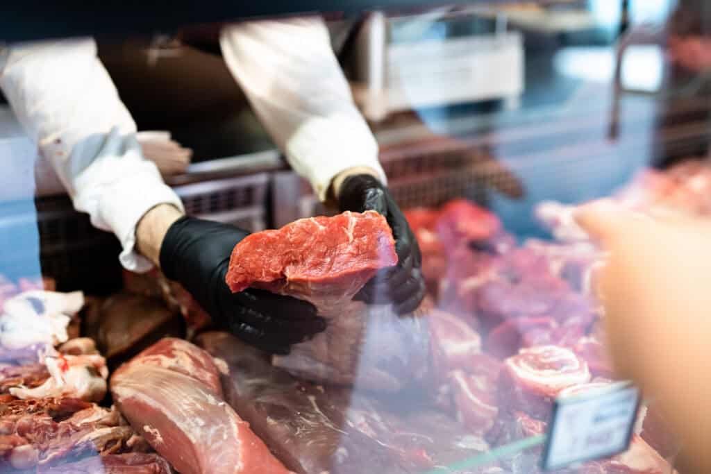 A butcher in black gloves carefully holds a large raw beef cut, similar to how skilled mediators handle complex cases.