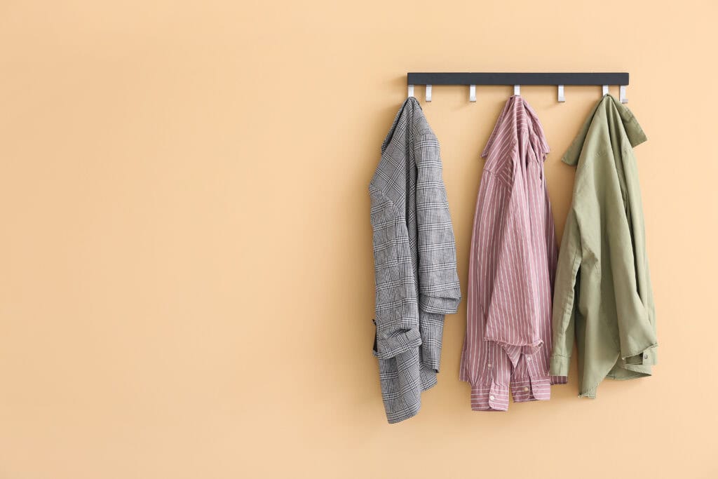 Three jackets hang on a black wall rack, suitable for professionals in legal or casualty mediation settings.
