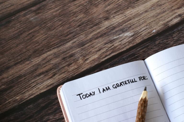 Open notebook on a wooden table, displaying “Today I am grateful for:” and notes about mediation services.