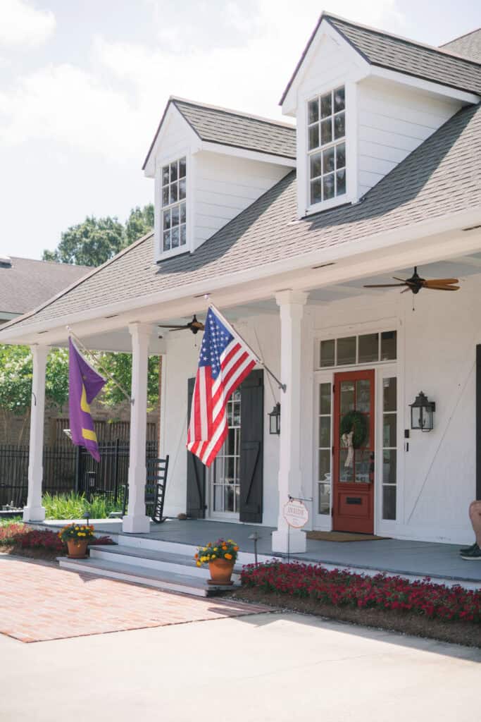 A welcoming white house with two dormer windows, flags, and a porch—suited for workers’ compensation legal mediation.