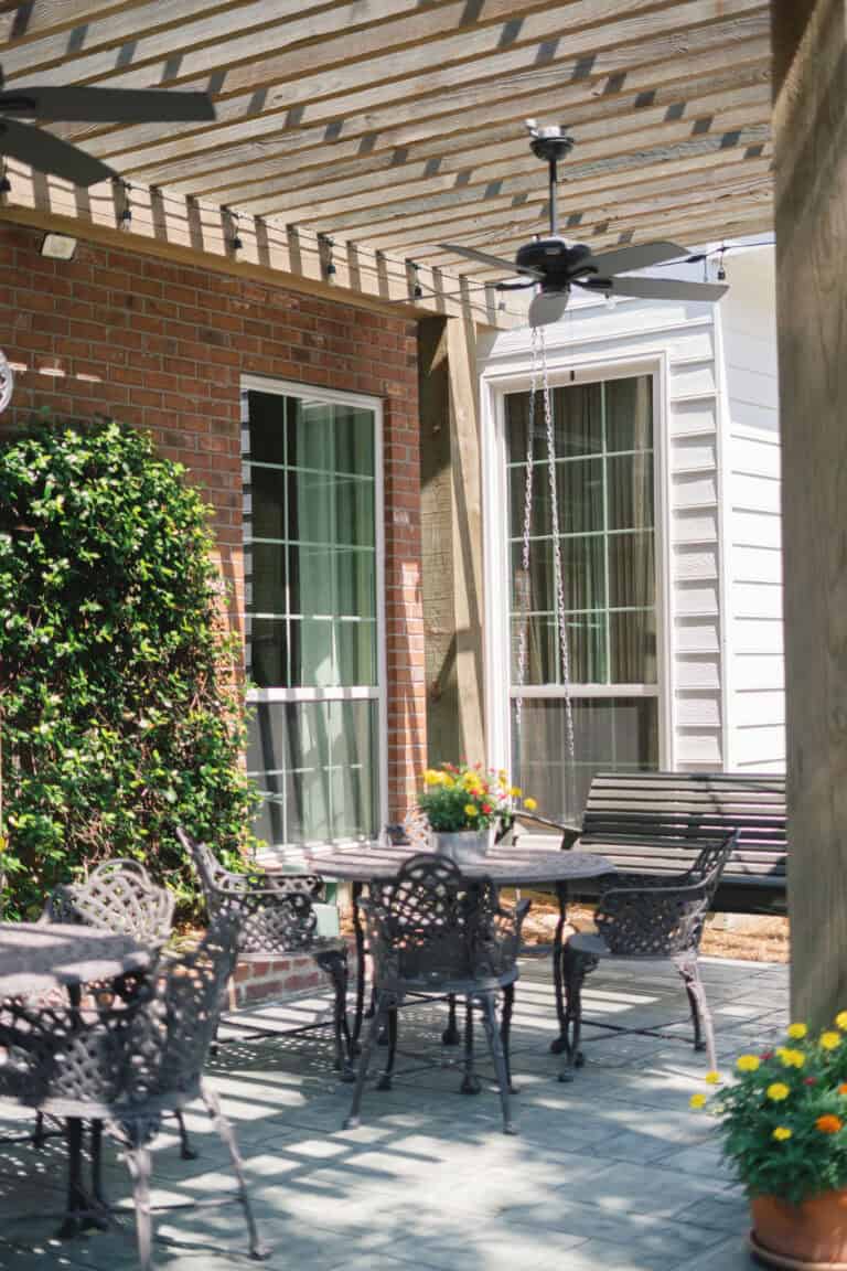Outdoor patio with metal tables, potted flowers, and a pergola—a relaxed setting for workers’ compensation mediation.