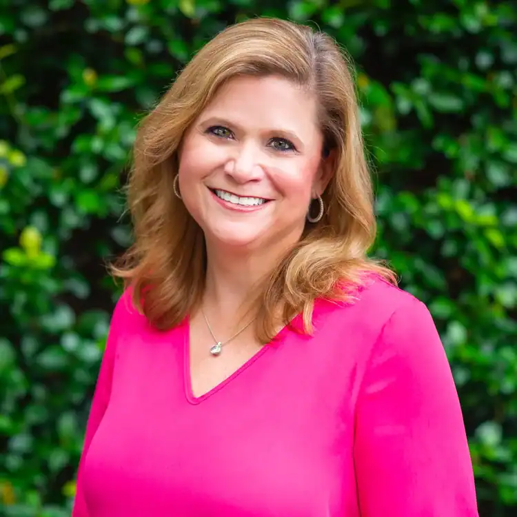 Smiling woman with shoulder-length blonde hair in a pink blouse, representing workers’ compensation legal mediation services.