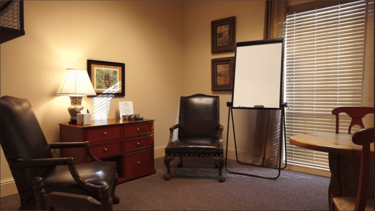 Professional office featuring two leather chairs, a red cabinet, and a flipchart suitable for legal mediation.