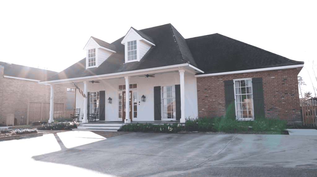 Brick house with white columns, a covered porch, and driveway—an inviting spot for relaxed legal mediation discussions.