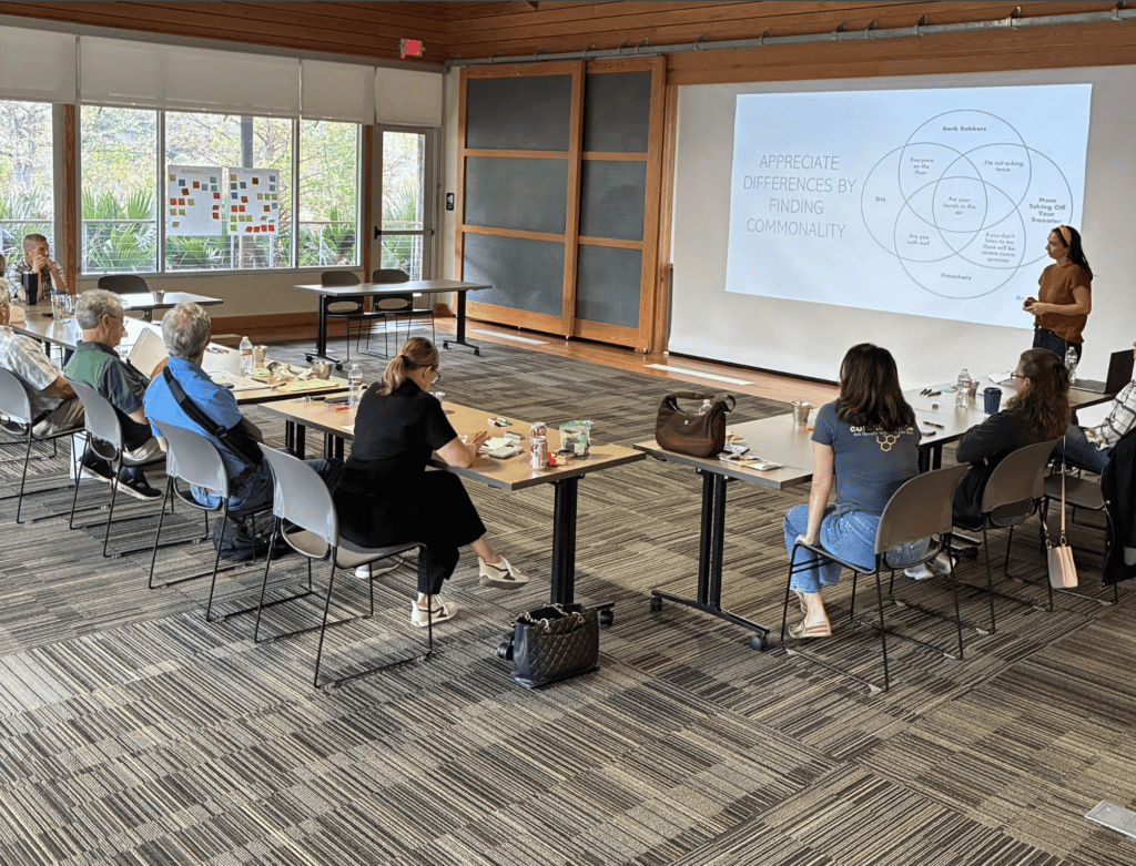 A woman shows a diagram on a screen to colleagues as they discuss mediation services in a conference room.
