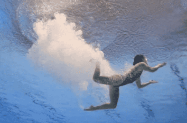 A swimmer glides underwater with bubbles trailing behind, illustrating clarity gained through mediation services.