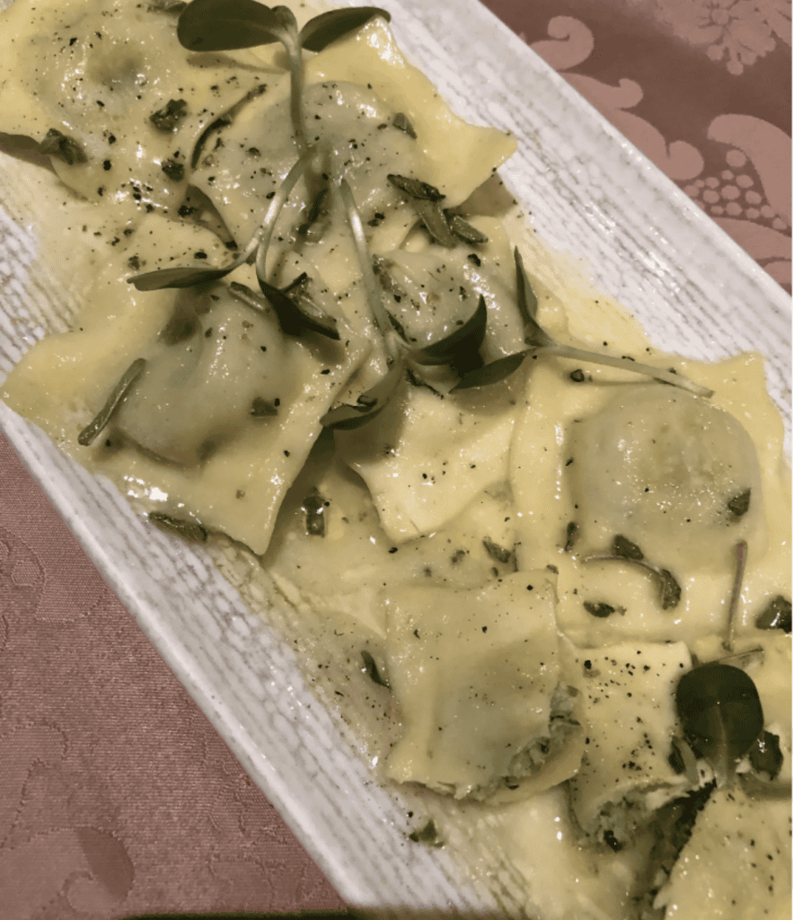 Ravioli on a rectangular plate, garnished with herbs and black pepper, arranged as neatly as a legal mediation table.