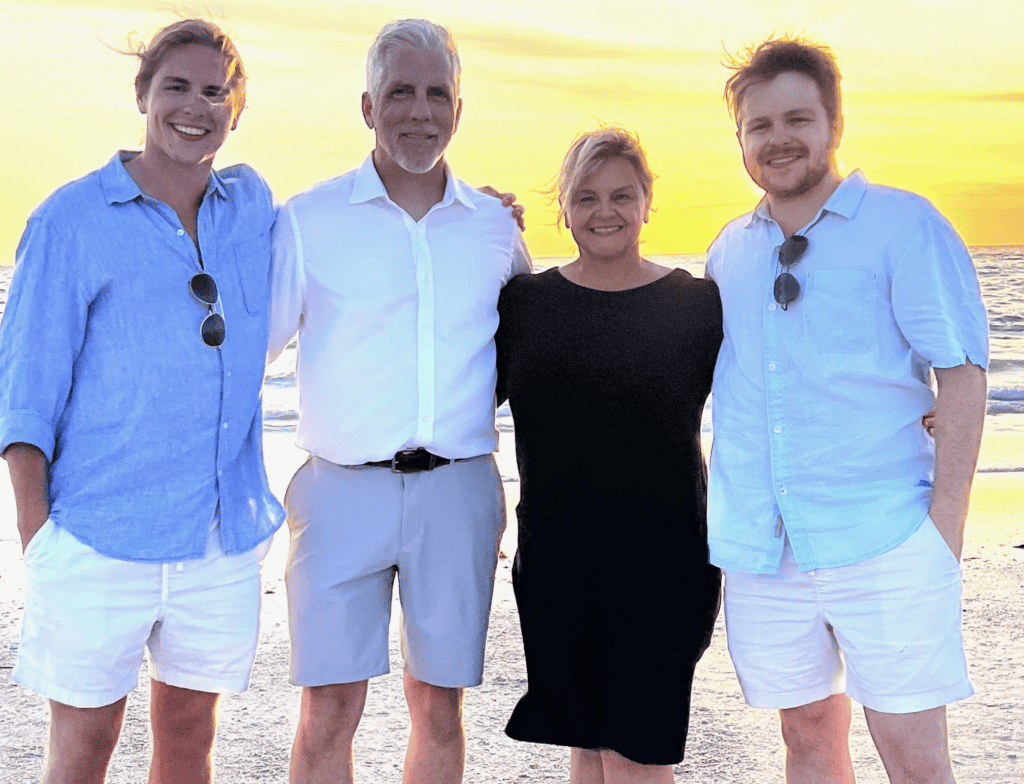Four people smile together on a beach at sunset after a longshore and harbor claims mediation by the gentle ocean.