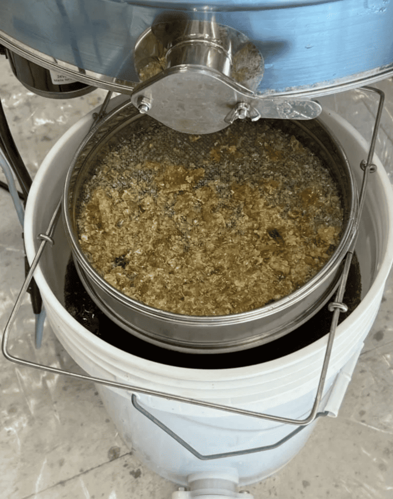 A honey extractor pours honey through a mesh sieve, resembling how mediation carefully filters and resolves complex disputes.