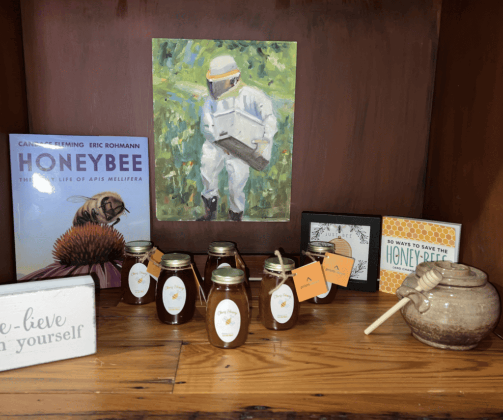 A shelf with honey jars, a beekeeper painting, and informational cards about legal mediation and workers’ compensation.
