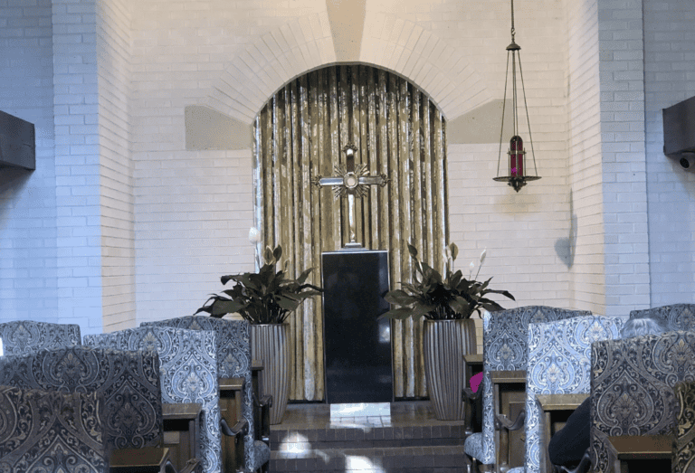 A small chapel features patterned chairs, a central altar, gold curtains, and plants, suited for reflection or mediation.