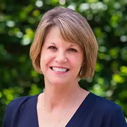 Smiling woman with short light brown hair outdoors, a specialist in workers’ compensation legal mediation.