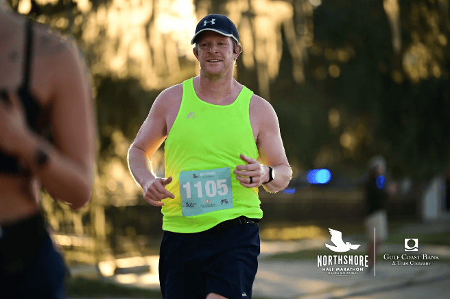 Runner in a neon yellow tank top, wearing bib 1105, competes in the Northshore Half Marathon sponsored by legal mediators.