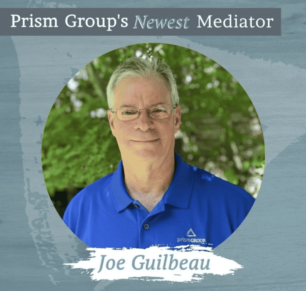 Joe Guilbeau, wearing glasses and a blue Prism Group polo, smiles while representing workers’ compensation mediation.